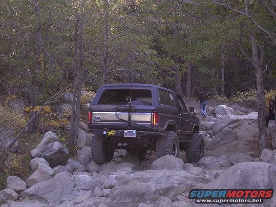 Dark blue SUV with lifted suspension and off-road tires navigating rocky terrain