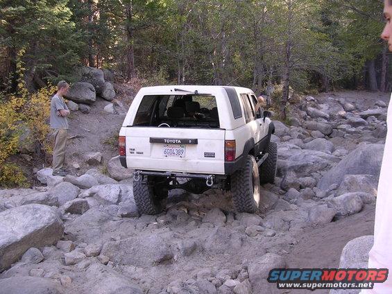 White 1985 Toyota 4Runner with off-road tires navigating a rocky path