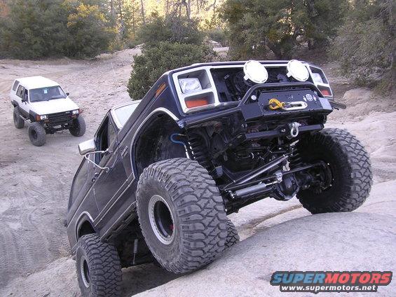 Dark blue off-road SUV with large tires and winch on rocky terrain