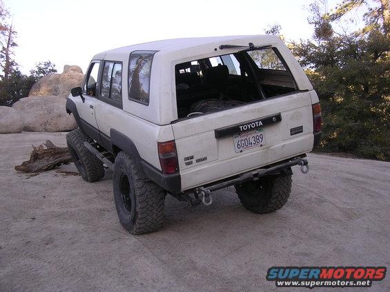 White Toyota 4Runner with a cap, lifted with large tires, on a dirt road