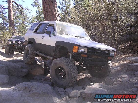 White 1985 Toyota 4Runner with large tires on rocky terrain