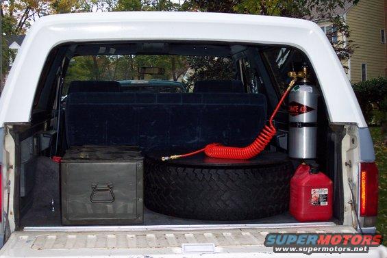White SUV cargo area with spare tire, toolbox, red gas can, and CO2 tank