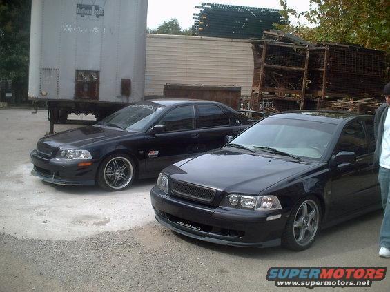 Two black sedans parked on gravel, one in foreground with a custom grille, the other behind it