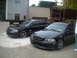 2006 Volkswagen GTI - Two black sedans are parked on a gravel lot with a large trailer and industrial debris in the background.