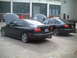 2006 Volkswagen GTI - Two black sedans are parked with their hoods open in front of an industrial building.