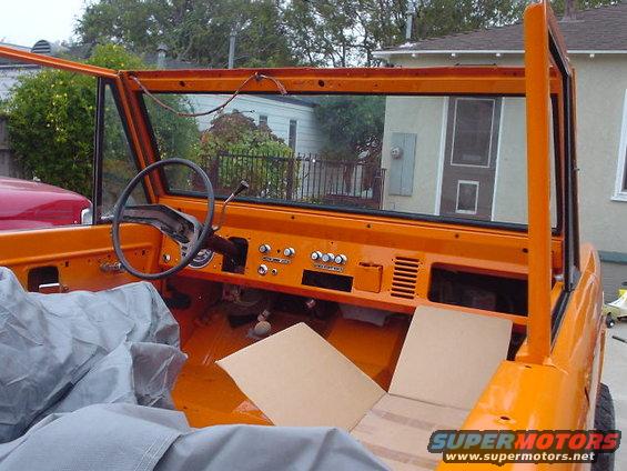 Orange 1977 Ford Bronco interior with dashboard, steering wheel, and seats covered