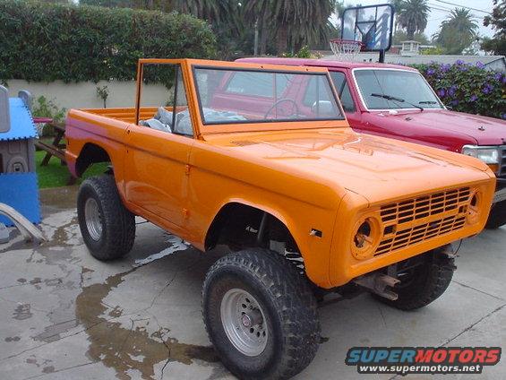 Orange 1977 Ford Bronco with a red Ford truck behind it