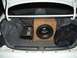 1997 Ford Probe - The trunk of a white car contains a subwoofer, amplifier, and a black bag.