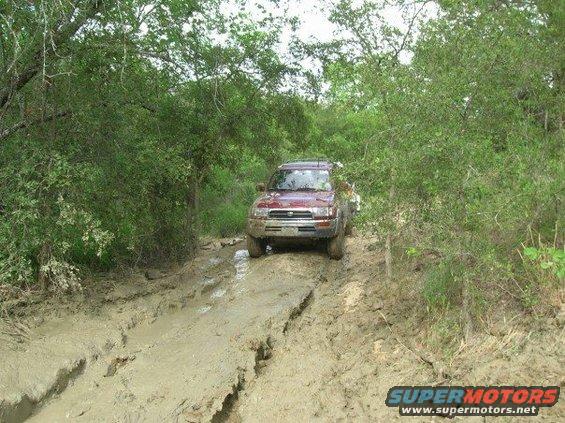 Red 1996 Toyota 4Runner driving on a muddy trail
