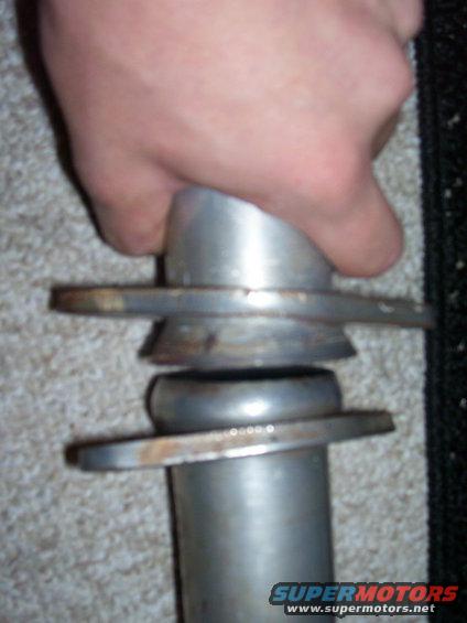 Hand holding a metal exhaust pipe section with flanges