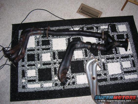 Exhaust headers on a rug, with a Supermotors.net logo