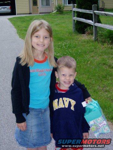 Girl with blonde hair and a boy wearing a navy hoodie stand on a driveway