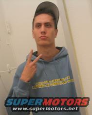 Man in blue hoodie with 'SUPERMOTORS' logo, making peace sign