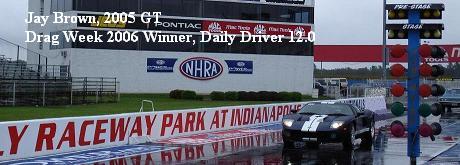 Black 2005 Ford GT with white racing stripes on a wet racetrack
