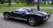 2005 Ford GT - A dark blue 2005 Ford GT with white racing stripes is parked in a driveway, viewed from the front three-quarter angle.