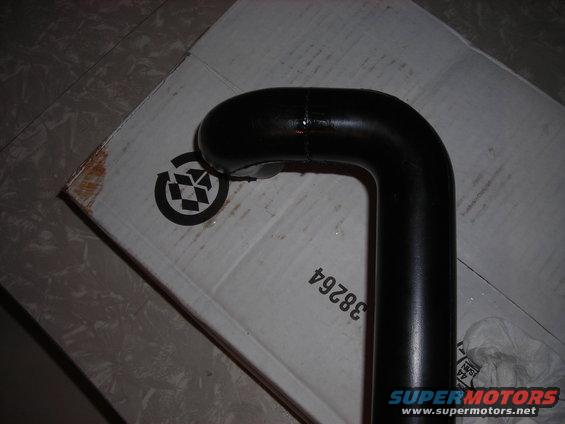 Black metal pipe with a bend, resting on a cardboard box with a recycling symbol and part number 38264