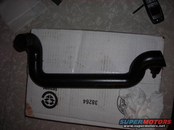 Black metal automotive pipe on a cardboard box, with a cell phone in the background