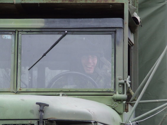 Driver in military truck interior, sticking tongue out