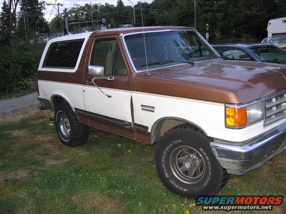 Brown and white 1987 Ford Bronco parked on grass, front passenger side visible