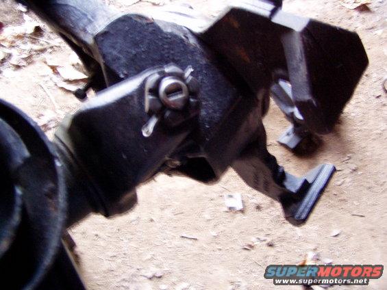 Close-up of a black metal vehicle suspension component with a pin and cotter clip