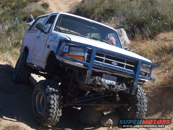 White 1995 Ford Bronco with blue bull bar on rocky terrain
