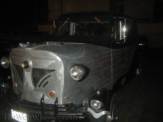 Custom riveted vehicle with a black top and silver body, parked at night