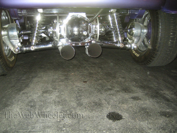 Custom rear axle with chrome differential, dual exhaust pipes, and suspension components. Tire has 'Rodi' visible