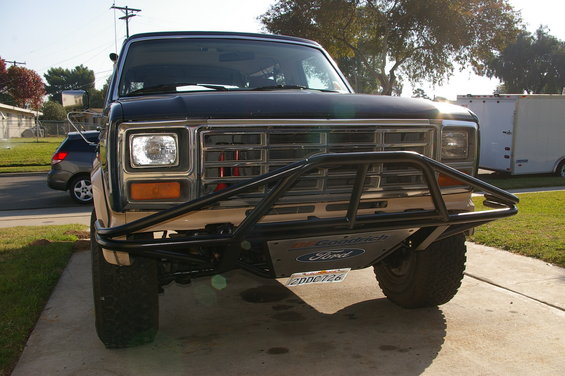 Front view of a dark blue Ford Bronco with a tan lower body and a black custom bumper. License plate reads 2DDC726
