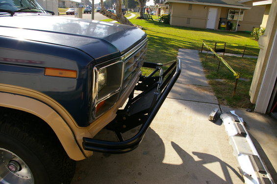 1986 Ford Bronco front end with blue paint, tan fender flares, and a black tubular bumper