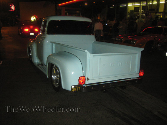 Rear view of a light blue 1953 Ford F-100 pickup truck with chrome wheels and a custom license plate