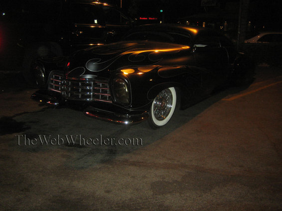 Black customized classic car with flame graphics and whitewall tires
