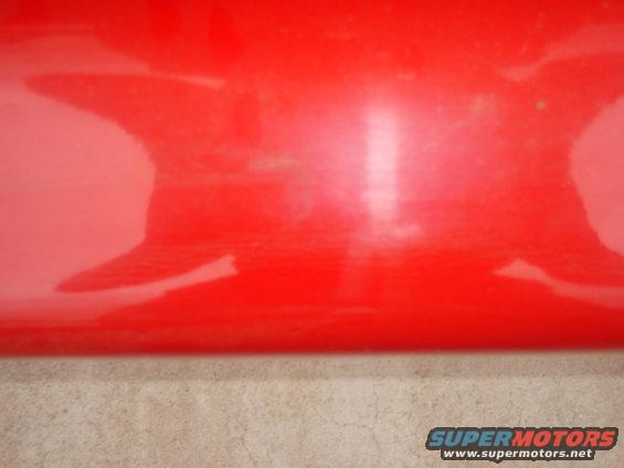 Red car panel with reflections and scuffs, close-up