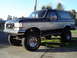 1989 Ford Bronco - This lifted 1989 Ford Bronco is parked on a sunny day, showing its two-tone paint job and off-road tires.