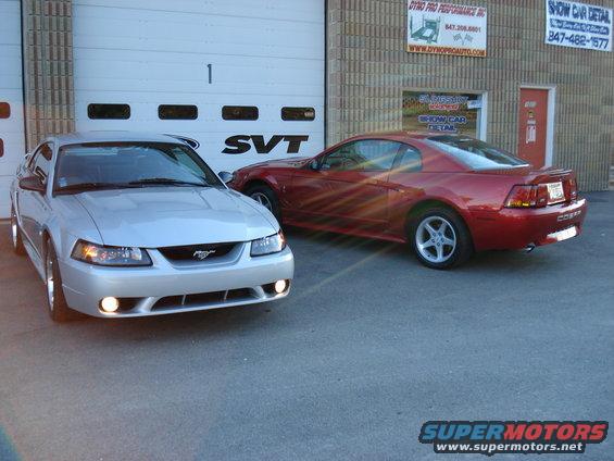 Silver Ford Mustang coupe parked in front of a garage door with SVT logo