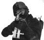 Person in helmet and tactical vest aims a rifle