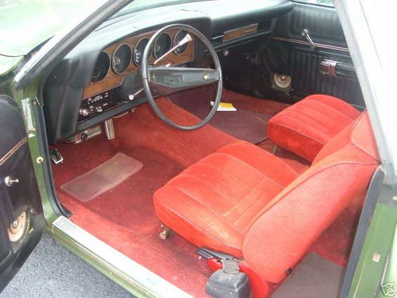 Green 1973 Ford Ranchero interior with red seats, wood-grain dashboard, and steering wheel