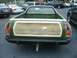 1973 Ford Ranchero - Rear view of a green Ford Ranchero with wood-grain tailgate, parked in a lot with other vehicles.