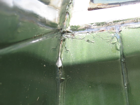 Green vehicle corner with peeling paint and rust around a window seal