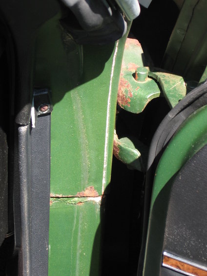 close-up of green car door jamb with visible rust on hinge area