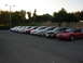 1995 Ford Taurus - A line of cars parked in a lot at dusk, with trees and a hill in the background.