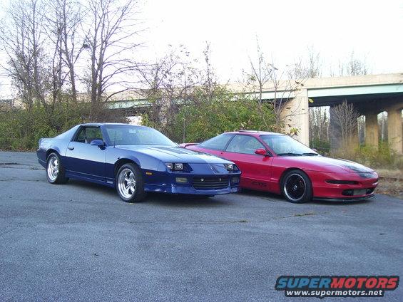 Red 1997 Ford Probe and blue Chevrolet Camaro parked on asphalt