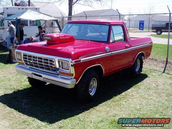 Red Ford Bronco with a large hood scoop and racing numbers on the fender