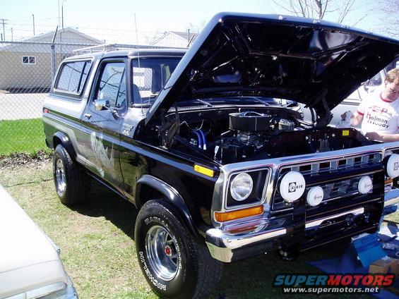 Black Ford Bronco with hood open, showing engine. Has aftermarket lights on front