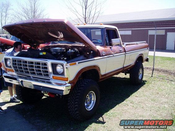 Brown and cream Ford pickup truck with hood open, showing engine. Lifted suspension and large tires