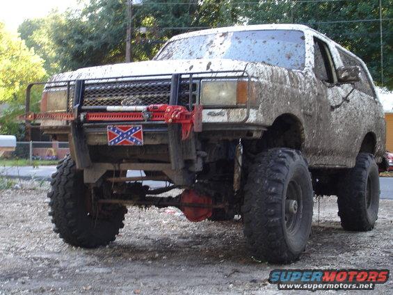 Mud-covered white 1987 Ford Bronco with off-road tires and a winch