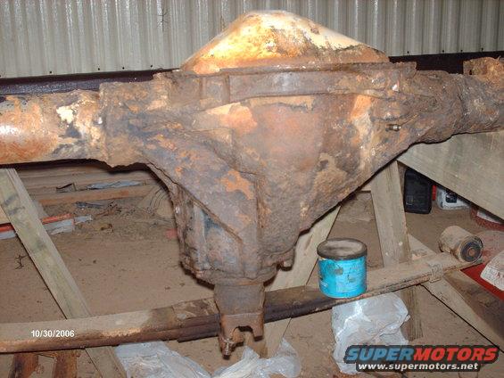 Rusty rear axle assembly with leaf springs, supported by wooden stands