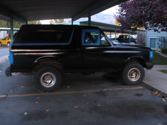 Side view of a black 1991 Ford Bronco with blue trim