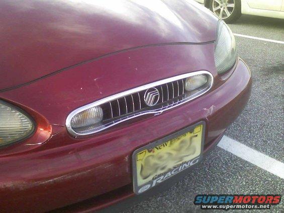 Red 1998 Mercury Sable front grille with chrome accents and a New Jersey license plate. Minor damage visible on the bumper