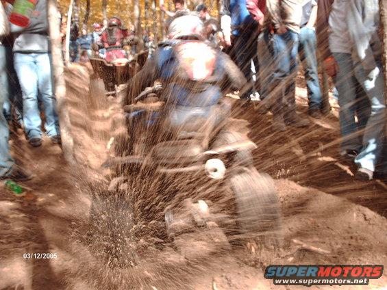 ATV splashing through mud with spectators watching