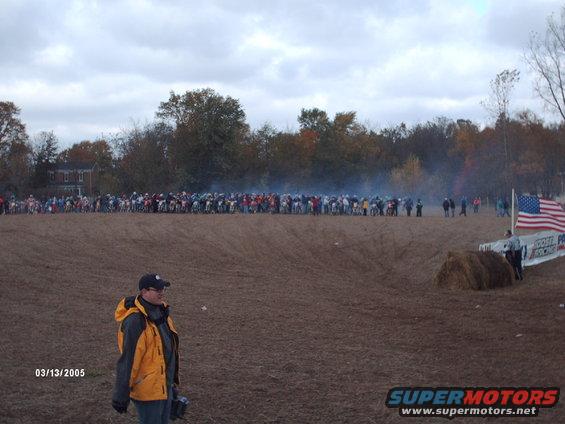 Motocross race start line with many motorcycles lined up, American flag flying